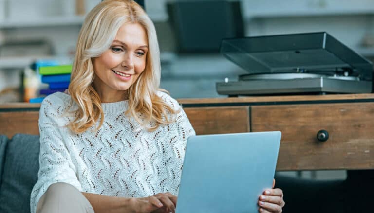Frau am Laptop mit Wohnzimmer im Hintergrund
