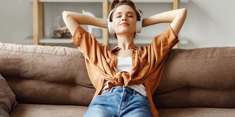 Hörangebot Alexa Echo Dot Frau liegend auf Couch mit Kopfhörern